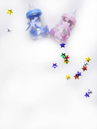 Is it a boy or a girl concept. Blue and pink toy bottles isolated on white, decoration with colorful stars. Twins baby shower. Baby announcement. Flat lay, copy spaceの写真素材
