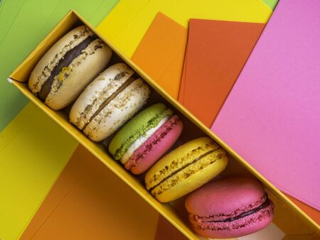 Colorful macaroons in box on festive colorful background, festive postcard