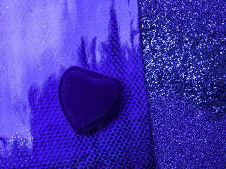 Blue velvet heart shaped ring box with glitters on trendy blue background. Gift for valentines day or birthday. Copy space for text, symbols of february romantic holiday or wedding designの写真素材