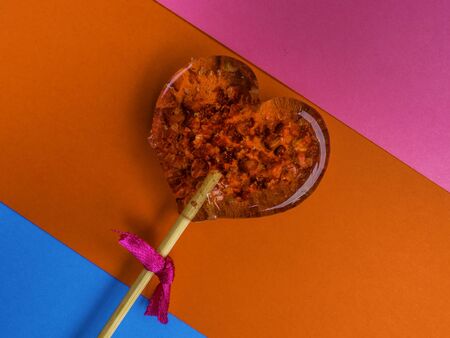 Single heart-shaped lollipop of valentines day on colorful, red, pink, blue backgroundの写真素材