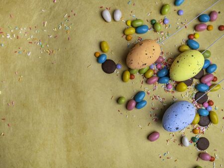 Colorful Easter eggs, multi - colored sweets on yellow background. Copy space