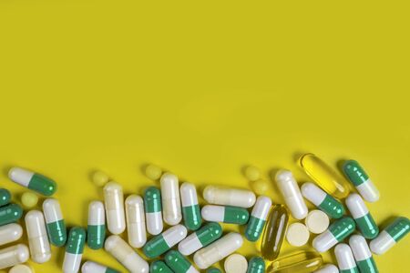 colorful pills, capsules and tablets on yellow background, Pharmacy and healthcare concept. Mixed vitamins, probiotics, nutrition, anti-aging beauty supplements, copy space, top viewの写真素材