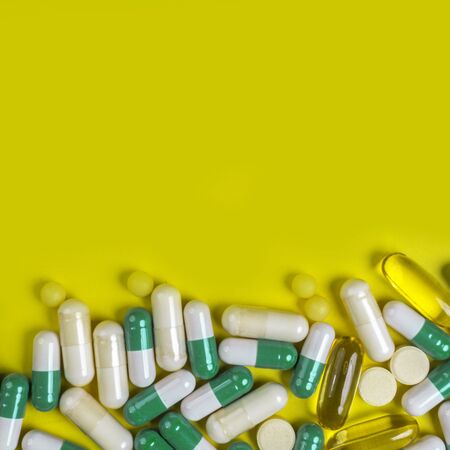 colorful pills, capsules and tablets on yellow background, Pharmacy and healthcare concept. Mixed...