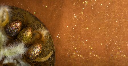 Top view of holiday card with gold red eggs, feathers with festive glitter confetti on vintage...