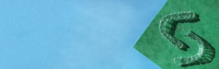 Banner of tooth transparent aligners or braces to straighten teeth in cosmetic dentistry and orthodontics on blue and green background, copy spaceの写真素材
