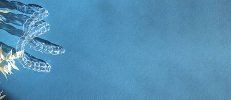 Invisible aligners teeth brackets on blue background with flower shadow
