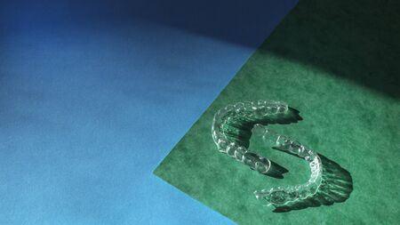 Banner of tooth transparent aligners or braces to straighten teeth in cosmetic dentistry and orthodontics on blue and green background, copy spaceの写真素材