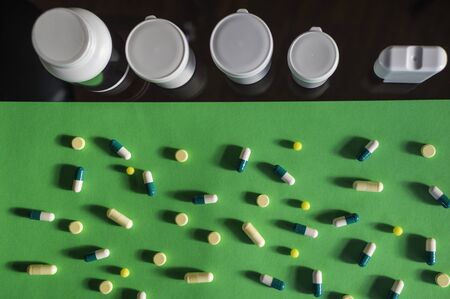 colorful pills and white bottles in green background, medicine, medical concept. Pharmacy theme