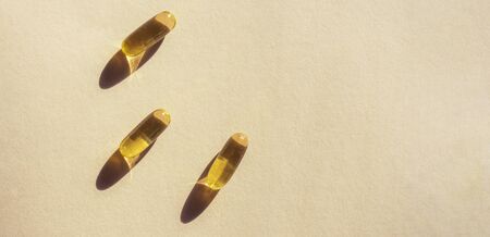 Oil yellow gelatin capsules on pink background, vitamins and antioxidant concept Omega 3, liver cod or evening primose oil for healthcare. Minimalism. Copy space.の写真素材