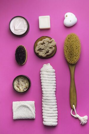 Scrub, lotion, soaps, cotton towel, peeling glove for body care on pink background. Spa eco friendly set kit, flat layの写真素材