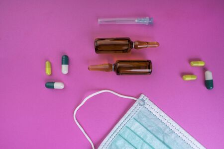 Protective face mask on pink background, therapy, prevention of virus flu, pills, ampoules, glass, antibiotics, needle, Medical pharmacy concept background,の写真素材