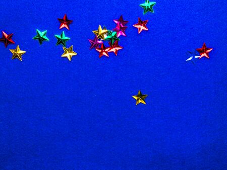 Festive colorful stars on trendy blue background. Holiday abstract concept flat-lay. Geeting card