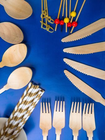 Disposable wooden cutlery on blue color background, drink tube, spoon, knife, fork cutlery, recycling, eco friendly, zero waste concept, plastic-free alternatives for environmental protectionの写真素材