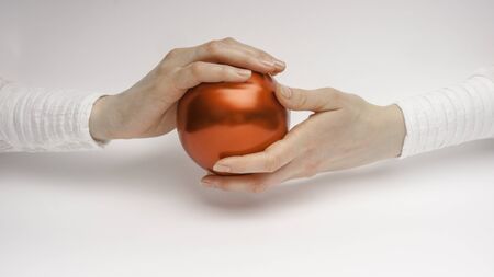 Close up of a woman hands holding a glass red ball as symbol of world protectionの写真素材