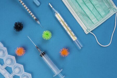 Protective medical mask, thermometer, syringe and viruses on blue backgroun, novel coronavirus -...