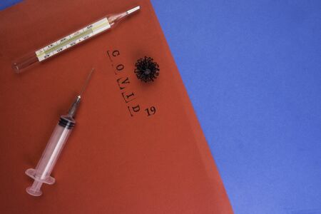 syringe, thermometer and virus in red and blue background with text covid 19, 2019-nCoV virus. Global pandemic. Vaccyne injection. Immunization and treatment from corona virus infection.の写真素材