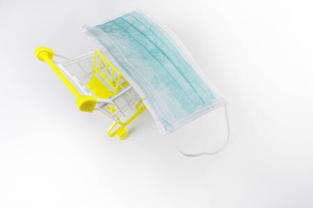 Medical face mask in a shopping cart, trolley on white background, personal protective and pharmacy online shopping conceptの写真素材