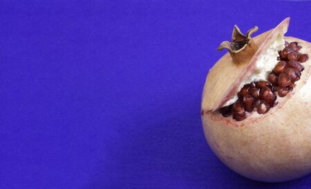 Juicy Fresh red ripe Pomegranate on blue background, heart healthy food concept, fruit antioxidants ability to impact oxidative stress make it a potential fertility aidの写真素材