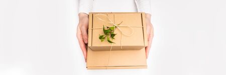 Woman hands holding a craft paper zero waste gift box. Christmas presents and New Year. Holiday...