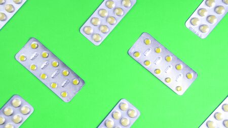 Tablet pills in blister packs pattern on green background. Medical preparations. Medical blue...