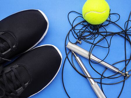 Sport equipment, sneakers, skipping rope, tennis yellow ball on blue background, Fitness, sport, healthy lifestyle concept. Flat lay, top viewの写真素材