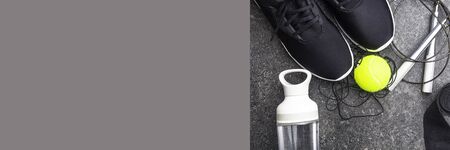 composition with sport equipment, black sneakers on concrete background, water bottle, tennis ball,...