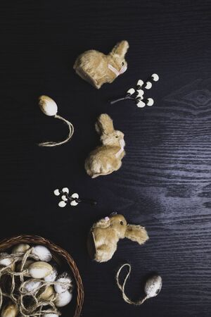 chocolate willow branches and cute bunnies with eggs in nest on black wooden background, happy Easter greeting card, spring festive season. Flat lay, top view, close upの写真素材