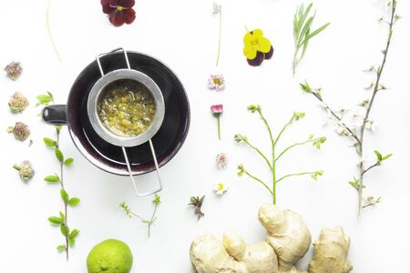 chamomile tea in clay cup, herbal flowers and leaf, ginger and lime, natural herbal medicine and...