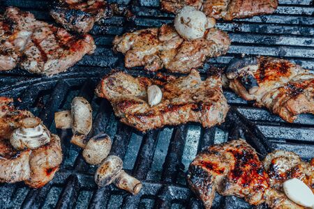 Pork barbecue on the big flaming grill, with moshrooms, outdoor summer party conceptの写真素材