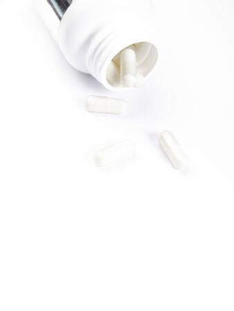 Bottle or container open with yellow pills, white background with copy space. Medicine white blankの写真素材