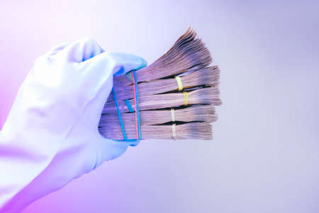 Hand projected with rubber glove holding, receiving or giving wad of European union Euro money cash banknotes, prevention virus spread, world money concept Corona virus COVID-19 outbreak. Copy space. Toned in modern neonの写真素材