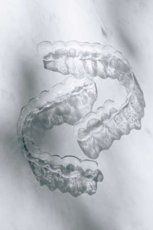 Modern tooth transparent aligners or braces to straighten teeth in cosmetic dentistry and orthodontics with trendy flower shadows, selective focusの写真素材