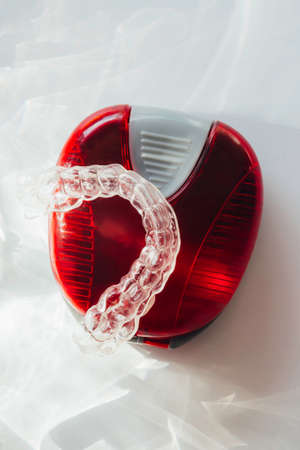 transparent braces or aligner to straighten teeth in cosmetic dentistry and orthodontics in red box with trendy shadowsの写真素材