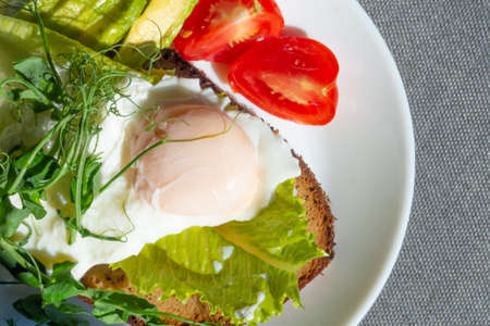 Poached eggs royale (benedict) on wholegrain bread, fresh orange and carrot juice, avocado, tomatoes, green salad microgreens. A healthy, delicious breakfast, snack or brunch. Close upの写真素材