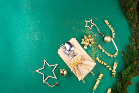 Christmas Green Festive Background with Cutlery, Holiday Setting Decorated with branches, toy, gold sparklesの写真素材