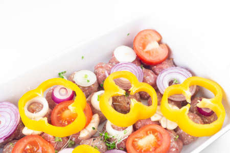 homemade raw organic mincet meat balls with onion, garlic, micro greens, bell peppers, tomatoes slices, uncooked, isolated on white, close up. Chinese food. Macroの写真素材
