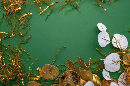 golden tropical eucalyptus leaves, gold metallic festive copper chip paper on beautiful green background. Top view, flat lay. Festive greeting floral card with space for your text. Templateの写真素材