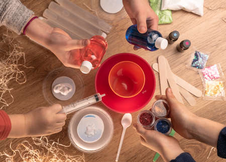 Kids hands making slime toy at home. Making slime. Ingredients and components mix, childrens...