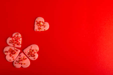 Cookies Red Heart Shaped folded into flower symbol for valentine's day on red background. Top view. Space for text. Treatsの写真素材