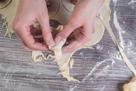 womans hands are making a dumpling on wooden table with flour, selective focus