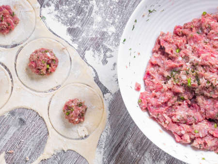 background of homemade meat dumplings or ravioli with meat. Traditional Russian national pelmeni food. Dough from flour and circles maked with glass, close upの写真素材