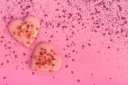 Valentines day heart shaped cookies dry strawberries on pink background with confetti. Top view....