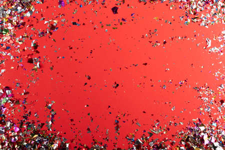 falling festive colorful confetti on red background. Christmas, birthday, Valentines day, party or holiday shiny backdrop. Flat-lay, top view. Greeting cardの写真素材