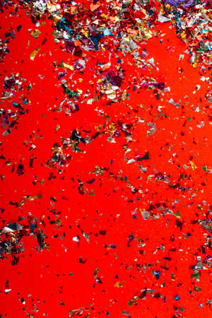 falling festive colorful confetti on red background. Christmas, birthday, Valentines day, party or...
