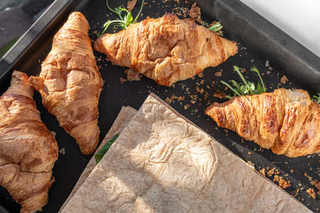 Delicious fresh baked Croissant and pita with cheese, microgreen sprouts in bakery black pan....