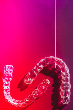 Transparent plastic dental teeth brackets tooth aligners, braces retainers to straighten teeth. Aesthetic and orthodontic modern retainerstoned in neon. Selective focusの写真素材