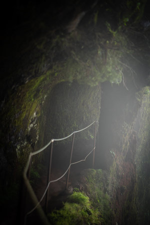 Foggy view of a dark cave with a metal fence in the middleの写真素材