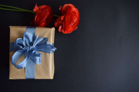 A gift and two red roses on a black backgroundの写真素材