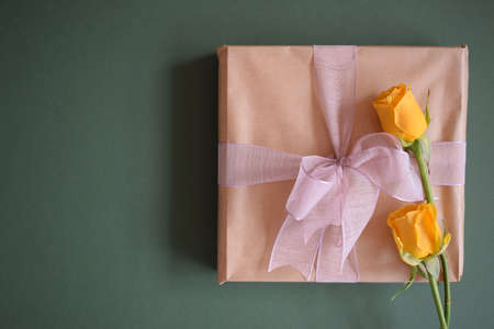 A beautiful gift and two yellow roses on a gray backgroundの写真素材