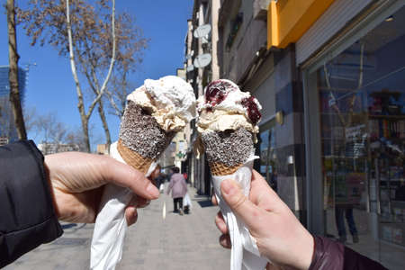 The hands of two girls holding in their hands the cone of melted ice cream waffle.の写真素材